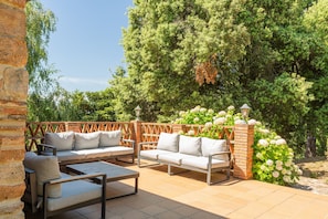 Eine Außenpatio mit einer Couch, Stühlen und einem Tisch.