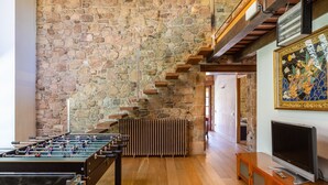 Una habitación con pared de piedra, mesa de fútbol de mesa, televisor y un mueble de madera.