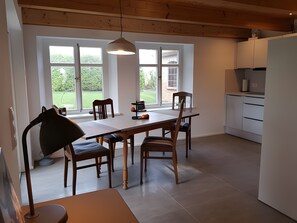 A modern kitchen with a dining area, large windows, and a pendant light.