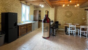 Una cocina rústica con vigas de madera a la vista, una botella grande de vino y un muro de piedra.