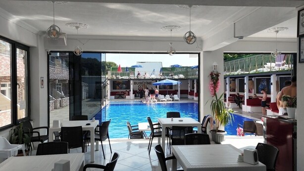 A poolside area with tables and chairs, a pool, and a view of the pool area.