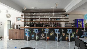 A bar area with shelves of glassware, a coffee machine, and a mural of drinks on the wall.