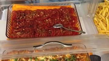 Une table de buffet avec trois plats en verre contenant différents mets, une cuillère et une fourchette.