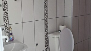 A bathroom with a toilet, sink, and a trash bin.