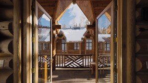 Une cabane en bois dotée d’un balcon, de balustrades en bois et offrant une vue sur des bâtiments enneigés.