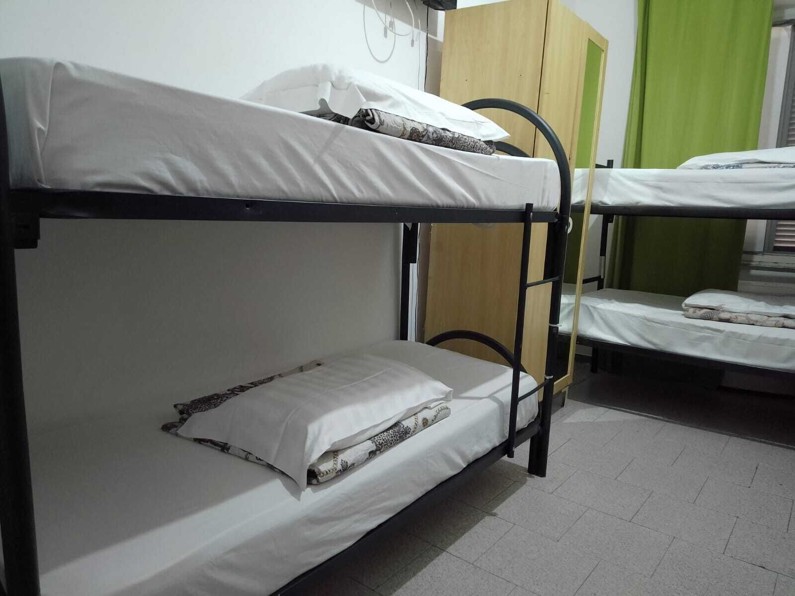 Ein Schlafzimmer mit Etagenbetten, einem Holzschrank und einem grünen Vorhang.