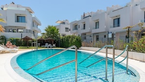 A swimming pool with metal ladders, surrounded by a tiled deck, and modern buildings in the background. - Holiday Home '5 Minutes From The Beach' with Sea View, Wi-Fi and Air Conditioning (Fuengirola)