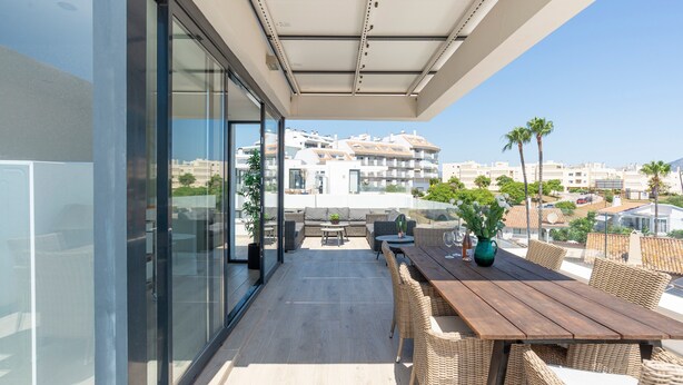 A balcony with wicker furniture, a wooden table, and a potted plant. - Holiday Home '5 Minutes From The Beach' with Sea View, Wi-Fi and Air Conditioning (Fuengirola)