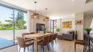 A modern dining area with a wooden table and chairs, a sofa, and a large window with a view of greenery. - Holiday Home '5 Minutes From The Beach' with Sea View, Wi-Fi and Air Conditioning (Fuengirola)