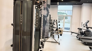 A gym with a rowing machine, weight bench, and treadmills. - PVH - Sunny Studio - Madison Residency (Dubai)