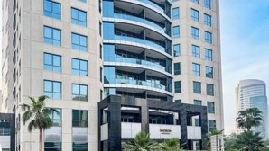 A modern building with multiple floors, large windows, and a prominent 'Madison' sign. - PVH - Sunny Studio - Madison Residency (Dubai)