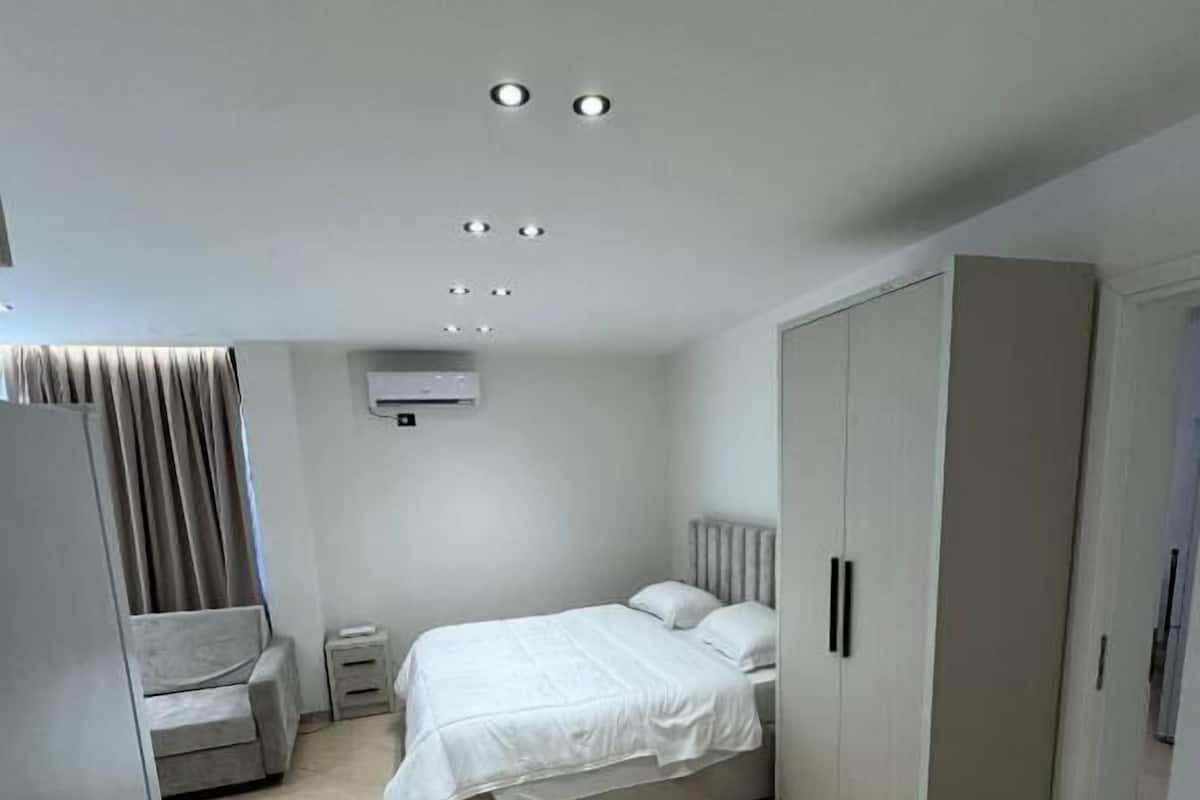 Une chambre moderne comprenant un lit, une armoire, une petite table de chevet et un appareil de climatisation.