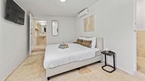 Een slaapkamer met een bed, nachtkastje, spiegel en een airconditioning.