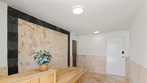 Een receptie met een houten balie, een mozaïekwand en een witte deur.