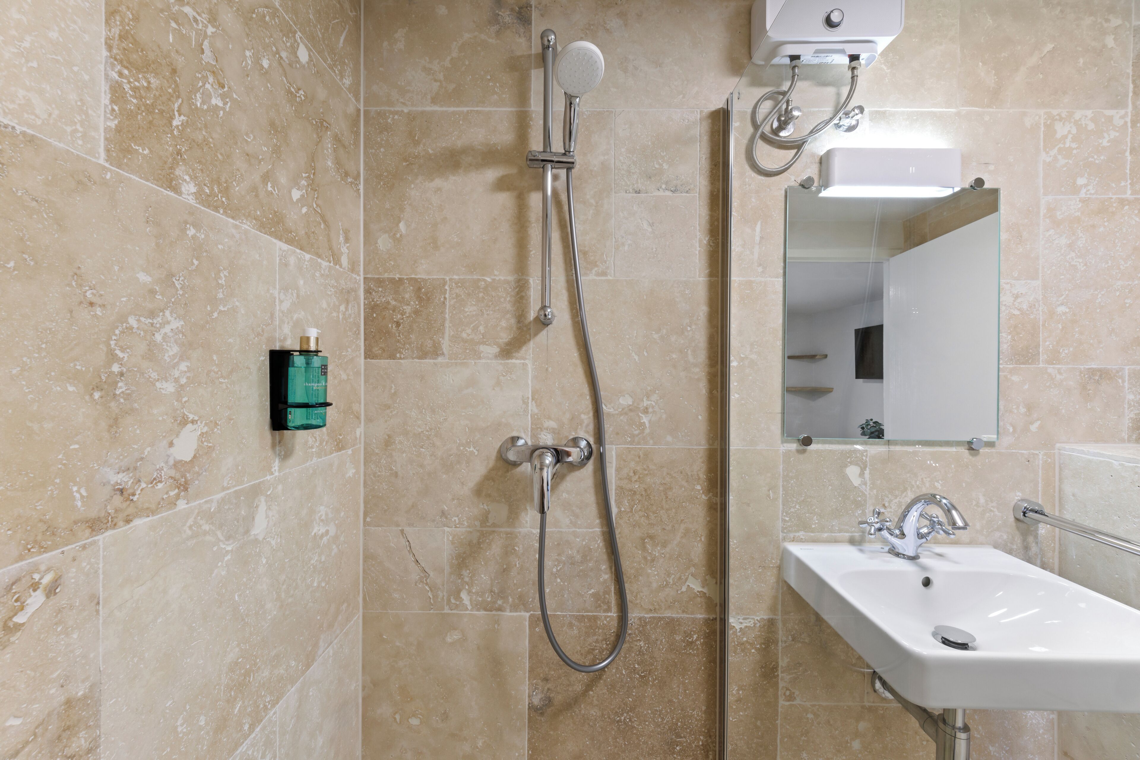 Ein Badezimmer mit Dusche, Waschbecken und Spiegel.