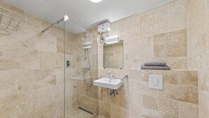 Een moderne badkamer met een douchecabine van glas, een wit wastafelmeubel en een spiegel erboven.