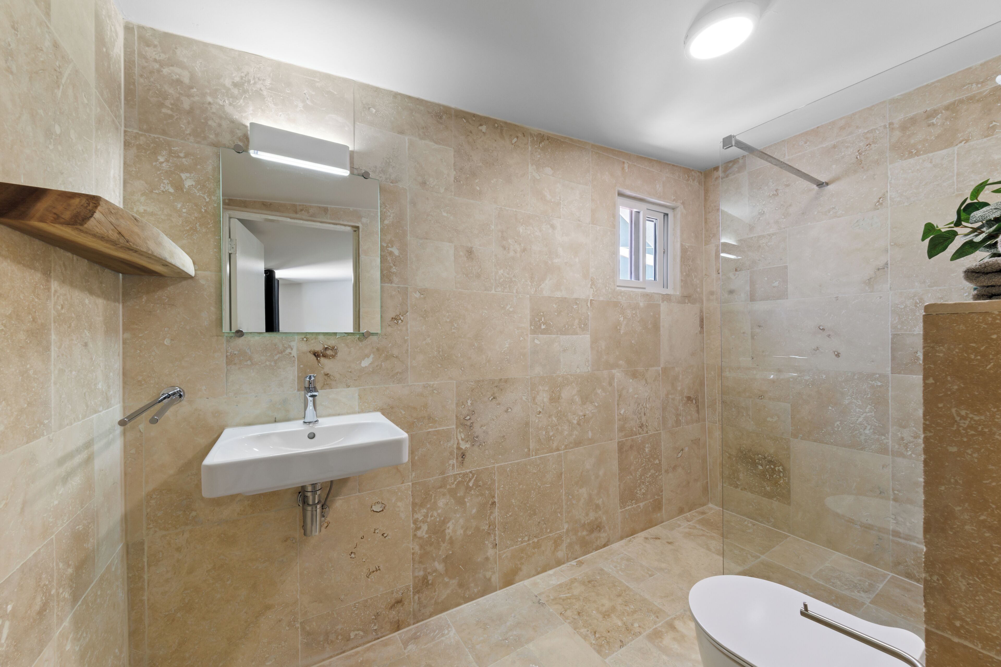 A modern bathroom with a sink, mirror, and shower.