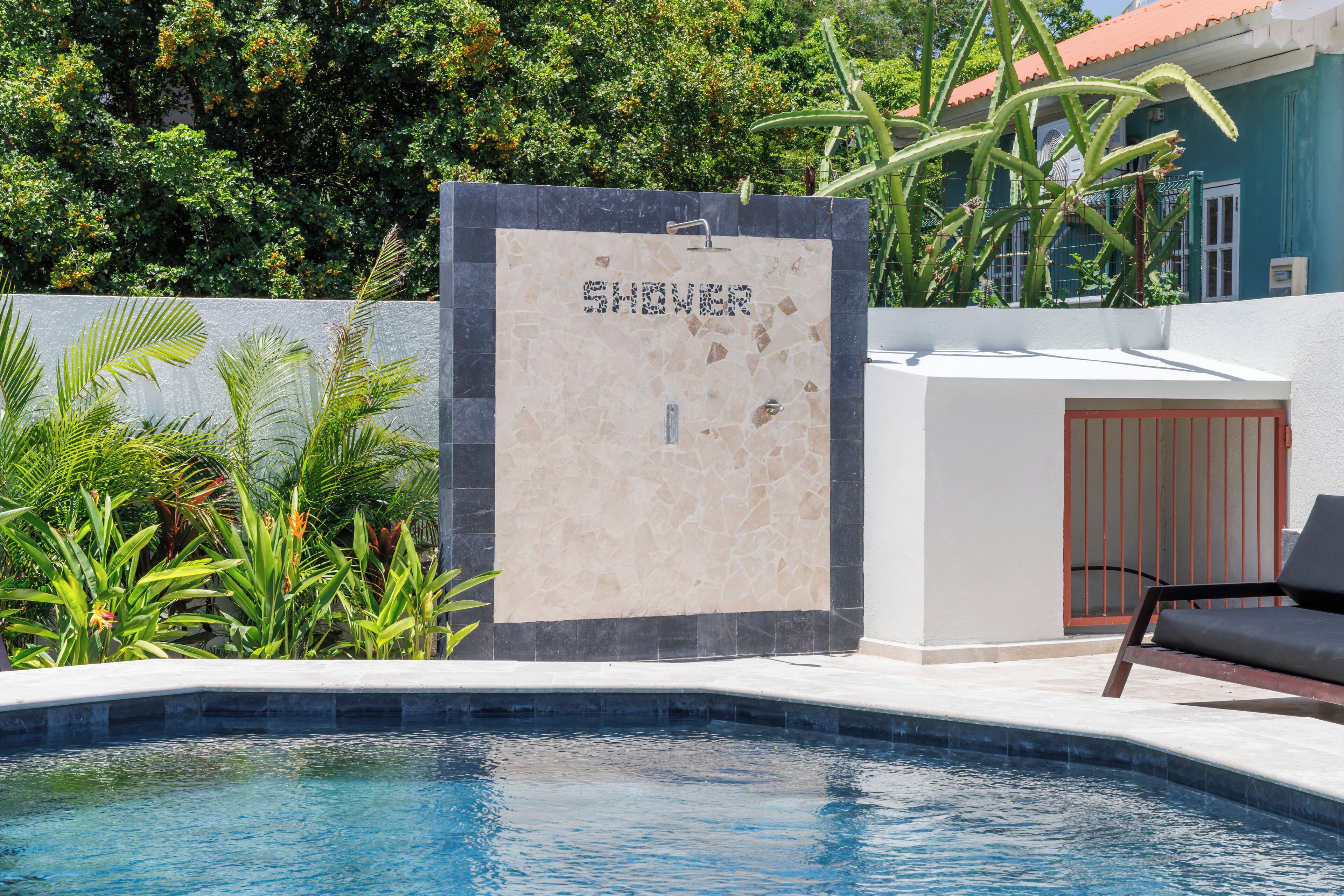 A pool area with a shower enclosure, a door, and a chair.