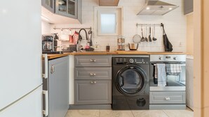 A compact kitchen with a washing machine, oven, and grey cabinets. - Apartment 'Sublime Centre D’aix' with Shared Terrace, Wi-Fi and Air Conditioning (Aix-en-Provence)