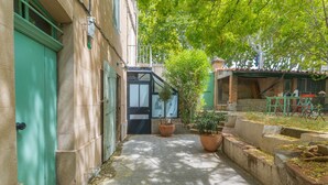 A narrow alleyway with a green door, a potted plant, and a small table with chairs. - Apartment 'Sublime Centre D’aix' with Shared Terrace, Wi-Fi and Air Conditioning (Aix-en-Provence)