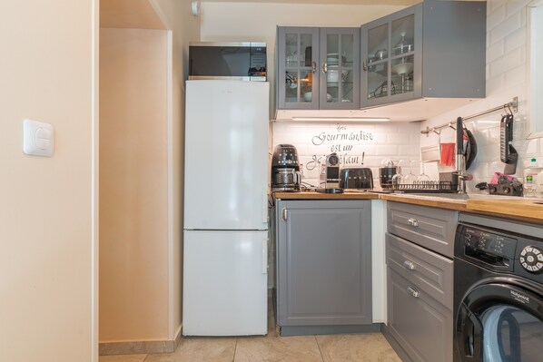 A compact kitchen with a refrigerator, a dishwasher, and a coffee maker.