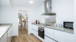 Een moderne keuken met witte kasten, een roestvrijstalen afzuigkap en een inbouwoven.