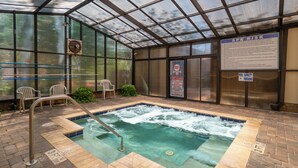 Un área de spa con un jacuzzi, un cartel que indica una capacidad de 18 personas para la piscina y un aviso sobre los riesgos del spa.