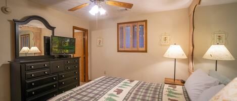 Un dormitorio con cama, cómoda, ventilador de techo y dos lámparas de pared.