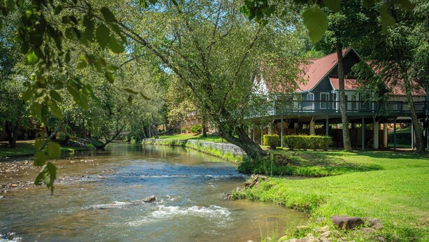 Vista al río con una casa que tiene balcón con vistas al agua.