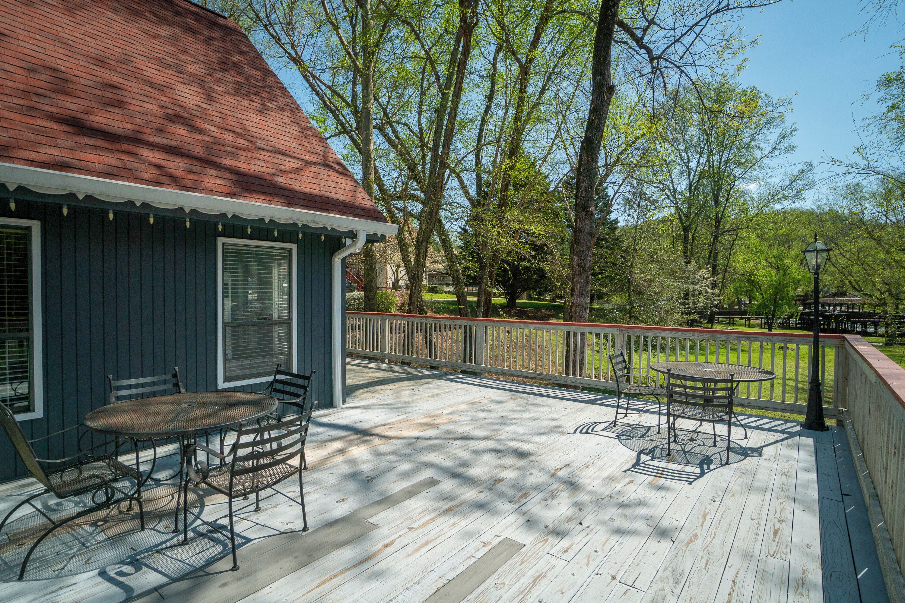 A wooden deck with outdoor furniture, a railing, and trees in the background.