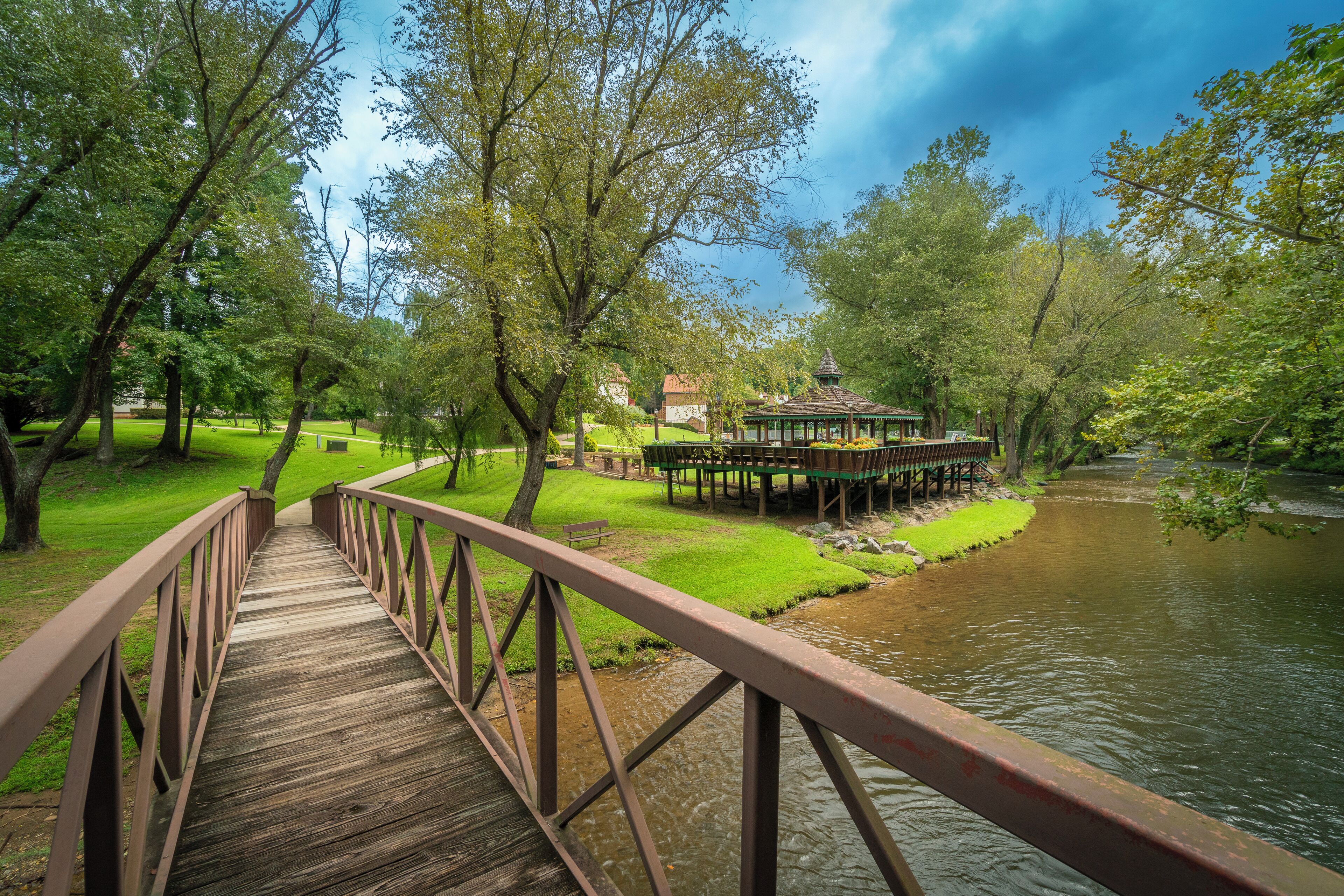 Un pont en bois enjambant une rivière, avec un kiosque situé sur la rive.