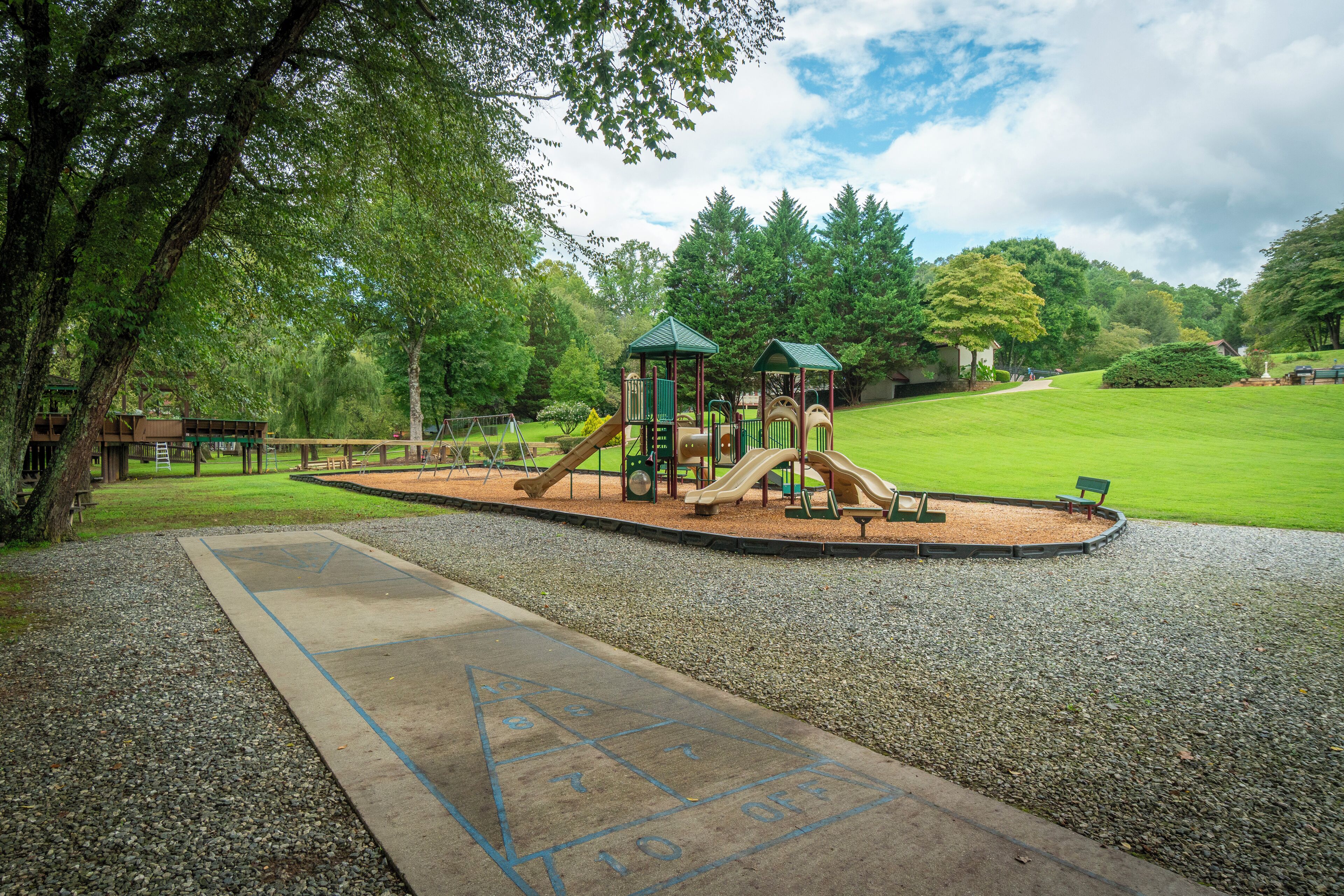 Un parque infantil con tobogán, estructuras para escalar y un campo de rayuela.