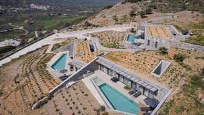 Een modern resort met meerdere zwembaden, terrassen en uitzicht op het omliggende landschap.