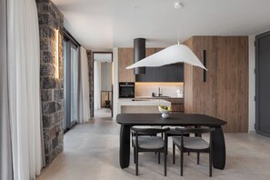Une cuisine moderne avec un mur en pierre, des meubles en bois et une table à manger noire avec des chaises.