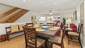 A spacious living area with a dining table, chairs, and a staircase.