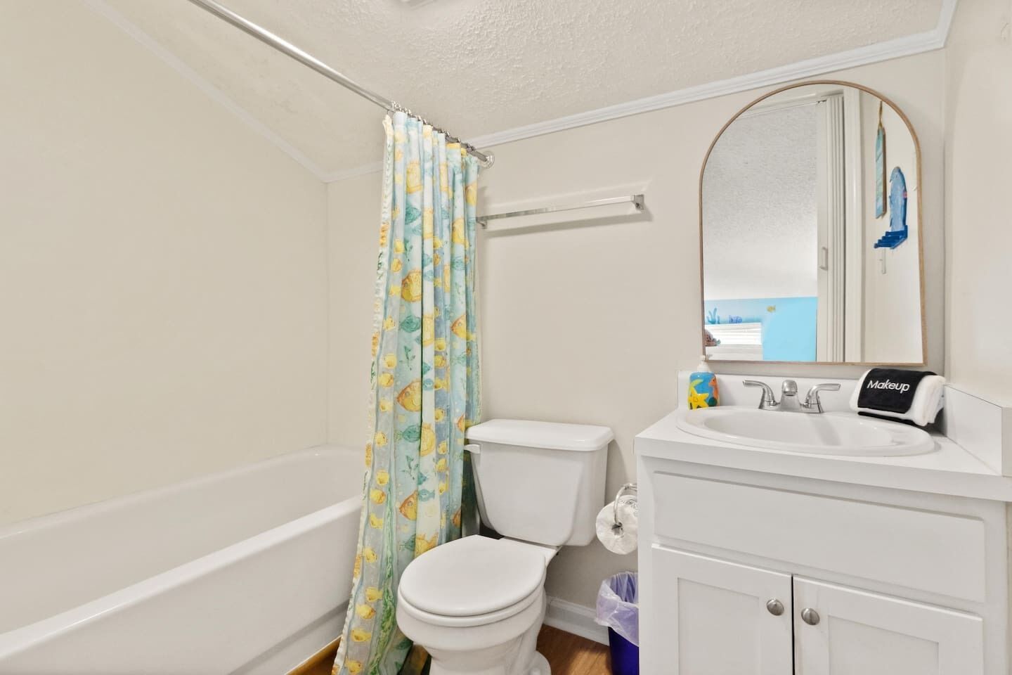 A bathroom with a toilet, a sink, a mirror, and a shower curtain.