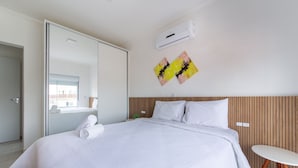 A modern hotel room with a large bed, a small table, and an air conditioning unit on the wall. - Modern apt w/ Barbecue 600m From the Beach Com305 (Florianópolis)