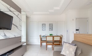 Un salon moderne doté d’un téléviseur à écran plat, d’un canapé et d’un coin repas avec une table et des chaises.