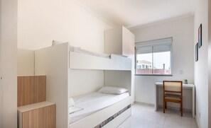 Une chambre compacte et moderne, équipée d’un lit superposé, d’un bureau et d’une chaise.