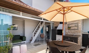 Un patio al aire libre con una mesa, sillas y una sombrilla grande.