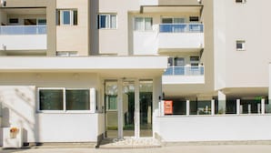 Ein mehrstöckiges Gebäude mit modernem architektonischen Design, mit Balkonen und einem Glastür.