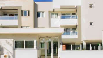 Un edificio de varios pisos con un diseño arquitectónico moderno, que incluye balcones y una entrada de vidrio.