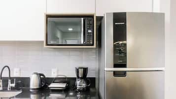 Una cocina equipada con microondas, cafetera y refrigerador.