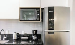 A kitchen with a microwave, coffee maker, and a stainless steel refrigerator.