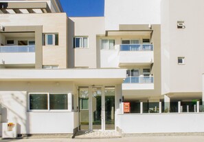 A multi-story building with a modern architectural design, featuring balconies and a glass entrance.