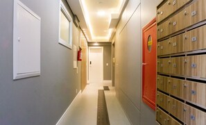 Un pasillo de hotel con taquilleras a la derecha y un extintor a la izquierda.