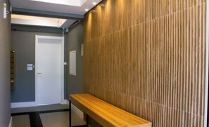 Un pasillo con un banco de madera, una puerta y un revestimiento de pared texturizado.
