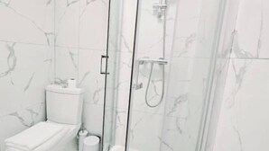 Een moderne badkamer met een douchecabine van glas, een toilet en een bidet.