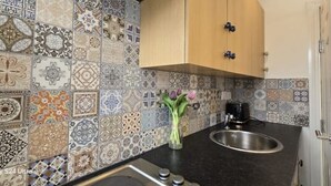 Een keuken met diverse betegelde patronen, een houten kast, een spoelbak en een vaas met bloemen.