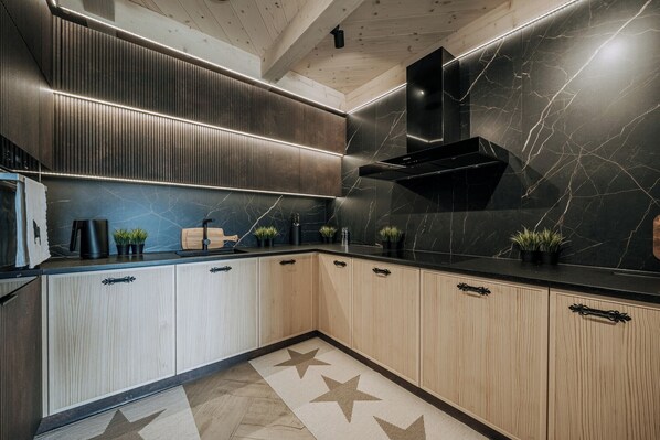 A modern kitchen with wooden cabinets, a black countertop, and a marble backsplash.